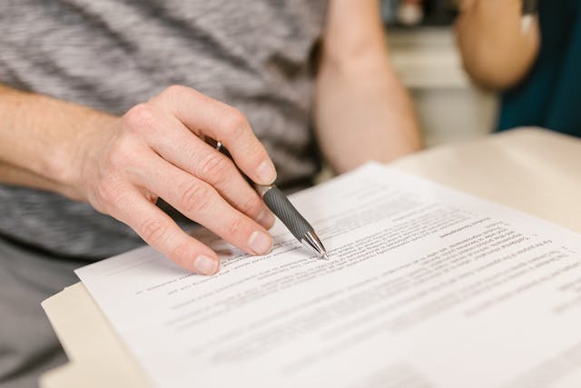 A person holding a pen over a piece of paper

Description automatically generated
