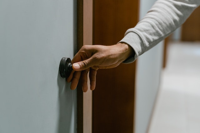 a person pressing on a doorbell with their thumb