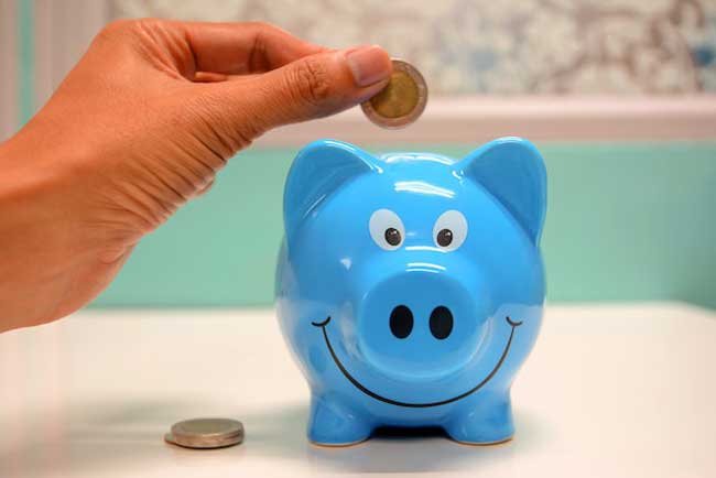 putting coins in blue piggy bank